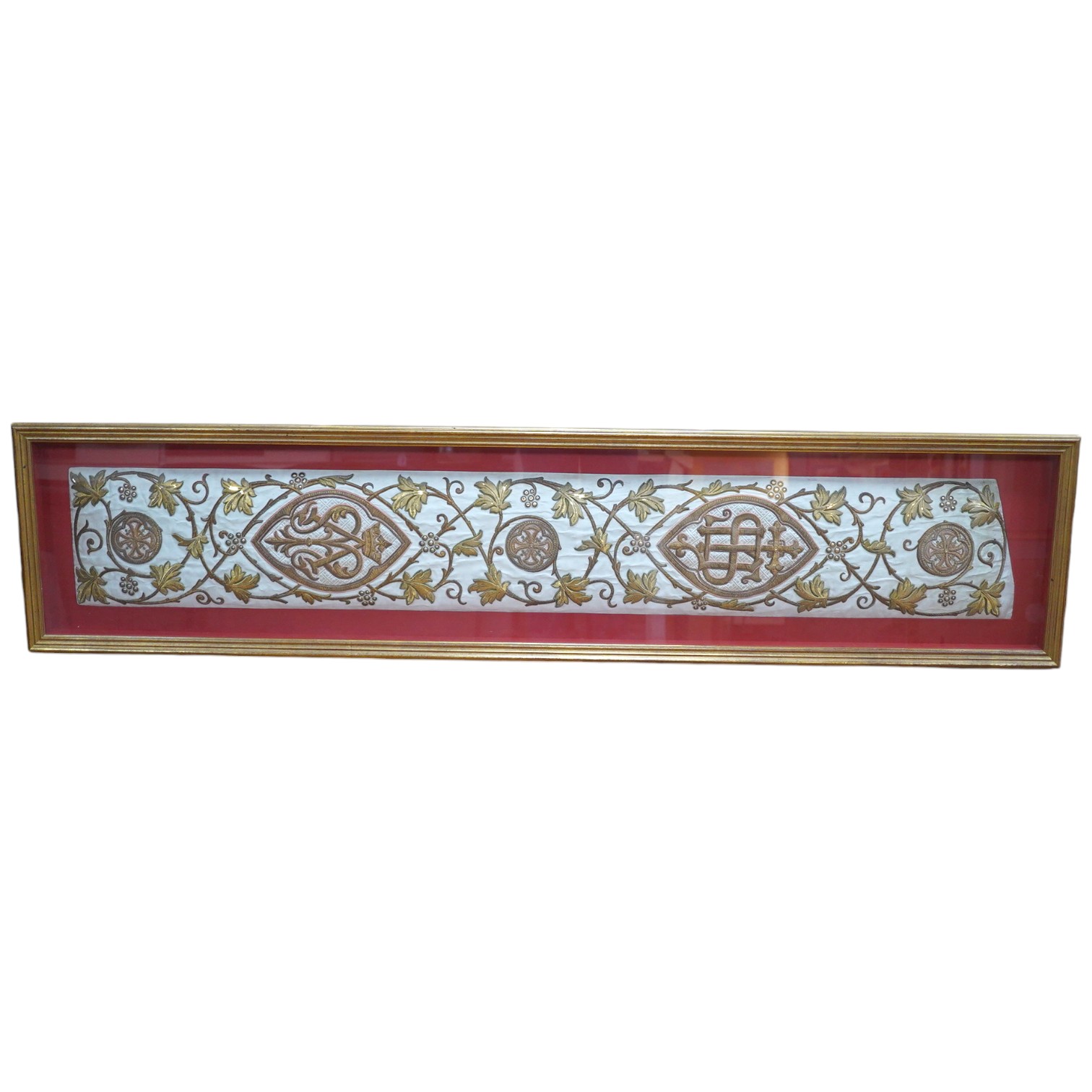 A framed Continental late 18th / 19th century heavily embroidered and deeply couched gold thread and white silk Orphrey panel, possibly part of a Chasuble or similar ecclesiastical garment, 18cm wide x 124cm long. Condit